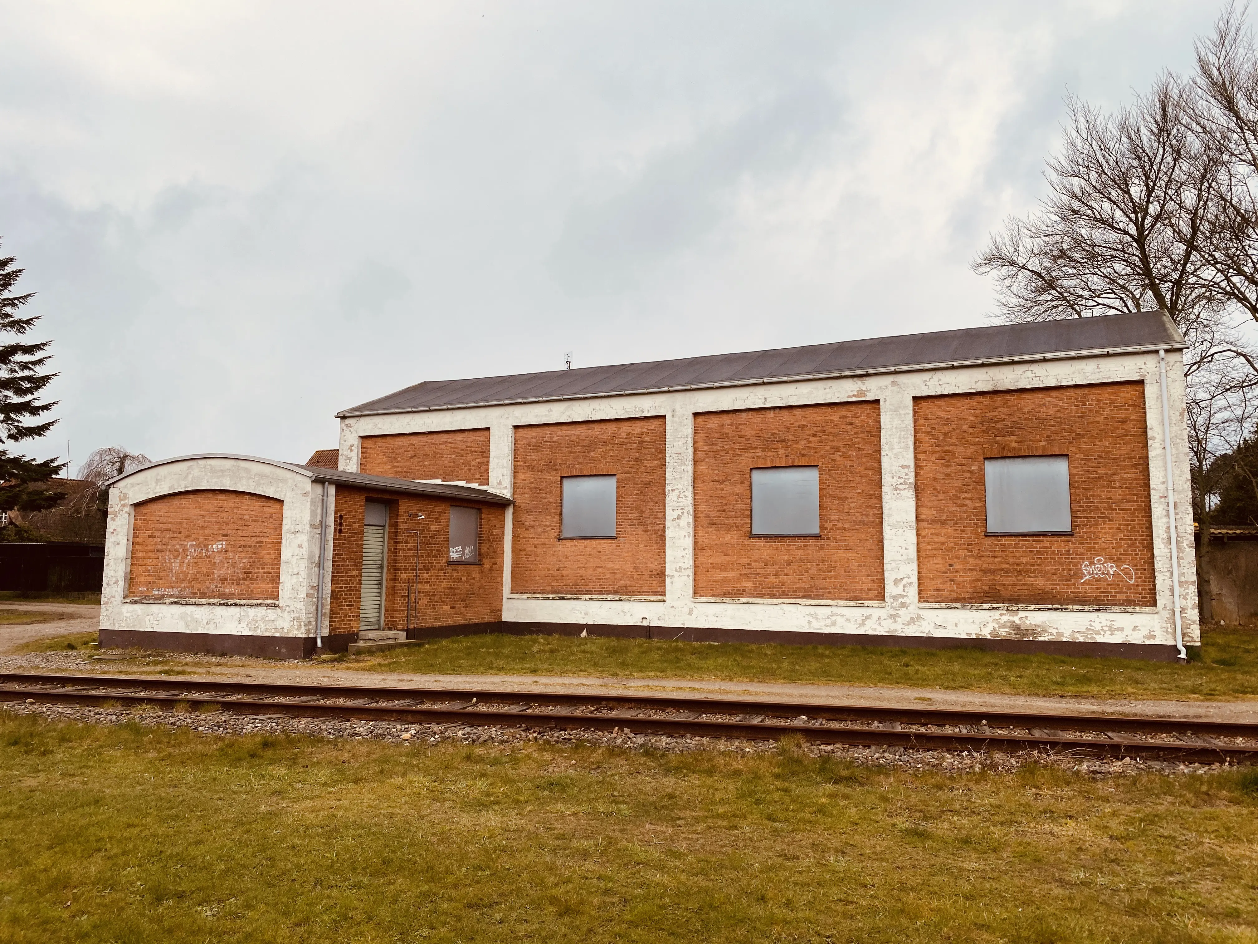 Billede af Haderslev Vestbanegård, som blev nedrevet 1985 (Stationsbygningen), men motorremisen fra 1951 eksistere stadig i 2020.