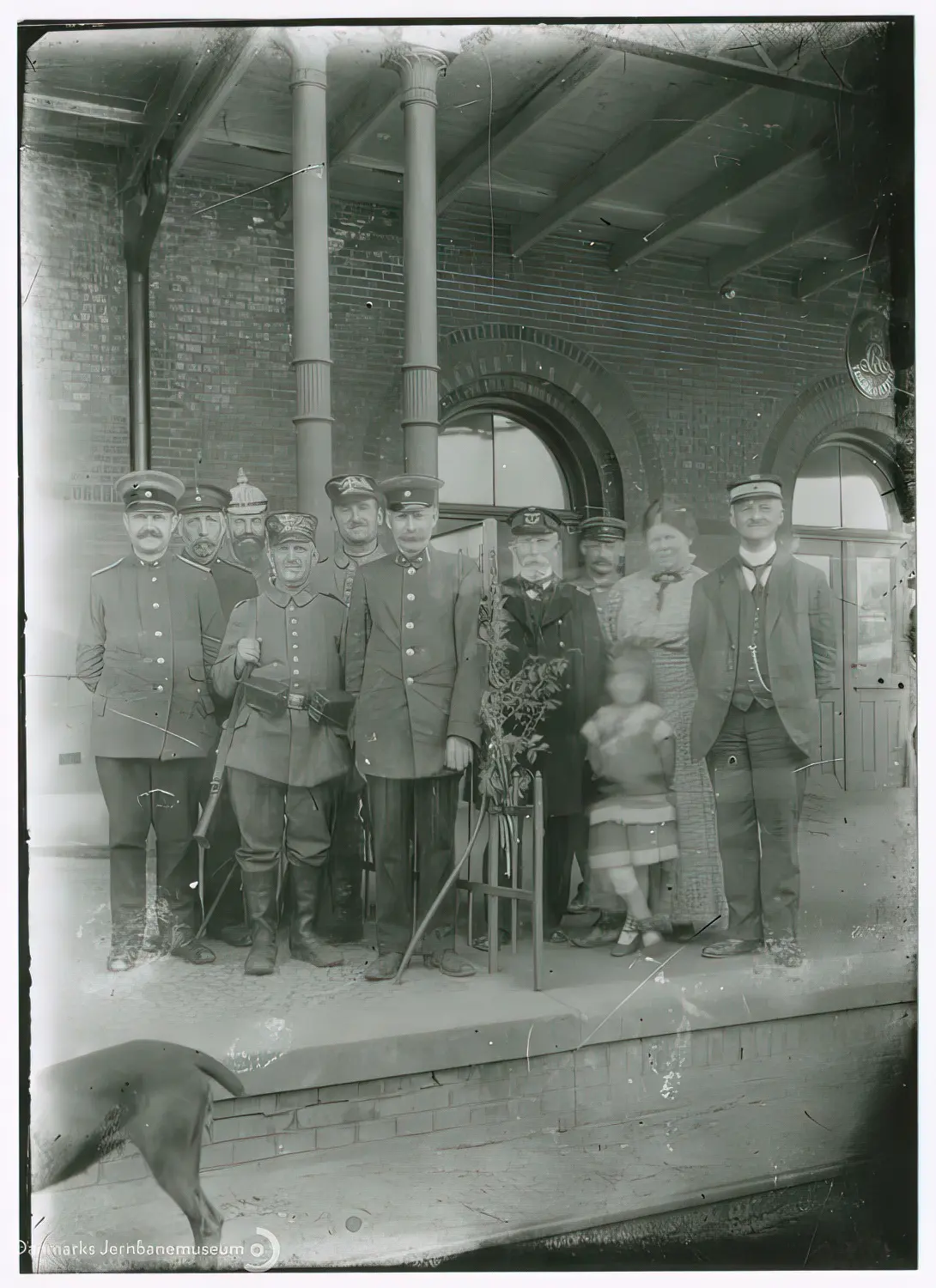 Billede af Vedsted-Hvidding Stations danske og tyske personale ved grænsestakittet på perronen. I midten stationsforstander Jens Jensen Høgdal, yderst th. muligvis toldkontrollør Mølgaard. De øvrige personer er uidentificerede.