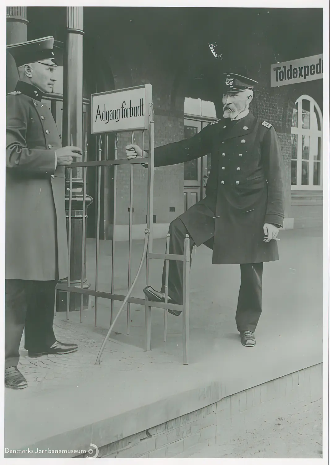 Billede af bahnhofsvorsteher Johan Friedrich Wilhelm Ehlers og stationsforstander Jens Jensen Høgdal i en cigarpassiar på tværs af perronens grænsestakit på Vedsted-Hvidding Station. Billede af bahnhofsvorsteher Johan Friedrich Wilhelm Ehlers og stationsforstander Jens Jensen Høgdal i en cigarpassiar på tværs af perronens grænsestakit på Vedsted-Hvidding Station.