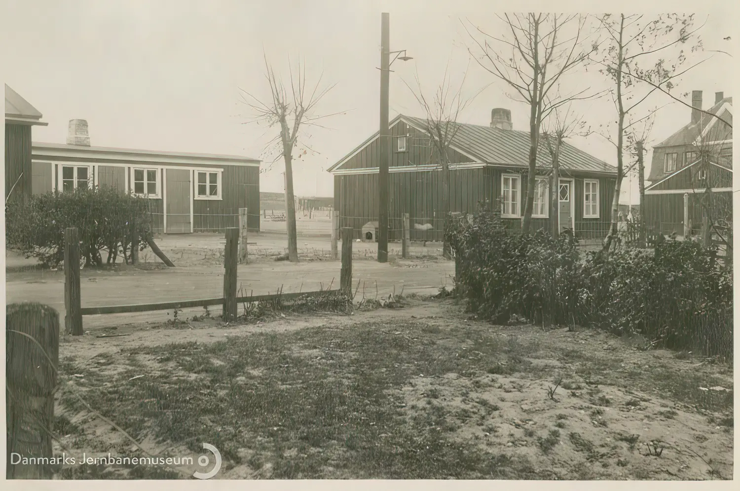 Billede af midlertidige boliger for jernbanefolk til Sønderborg Hovedbanegård efter Genforeningen. En fælles retiradebygning mellem tjenesteboligerne på Skrænten. Til højre svellehuset Skrænten 26.