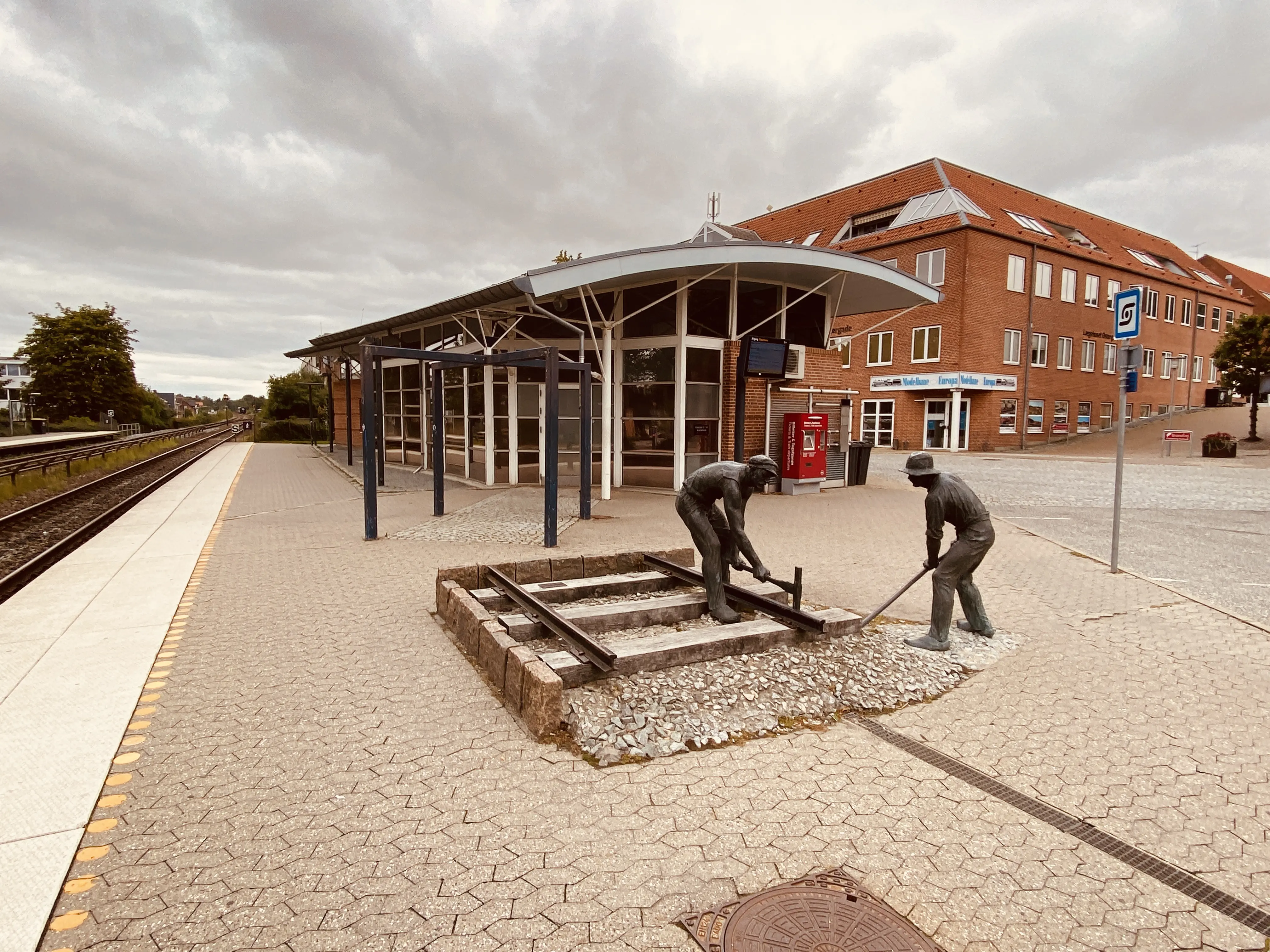 Billede af skulpturen af jernbanebørsterne ved den nye Hadsten Stations stationsbygning i Hadsten.