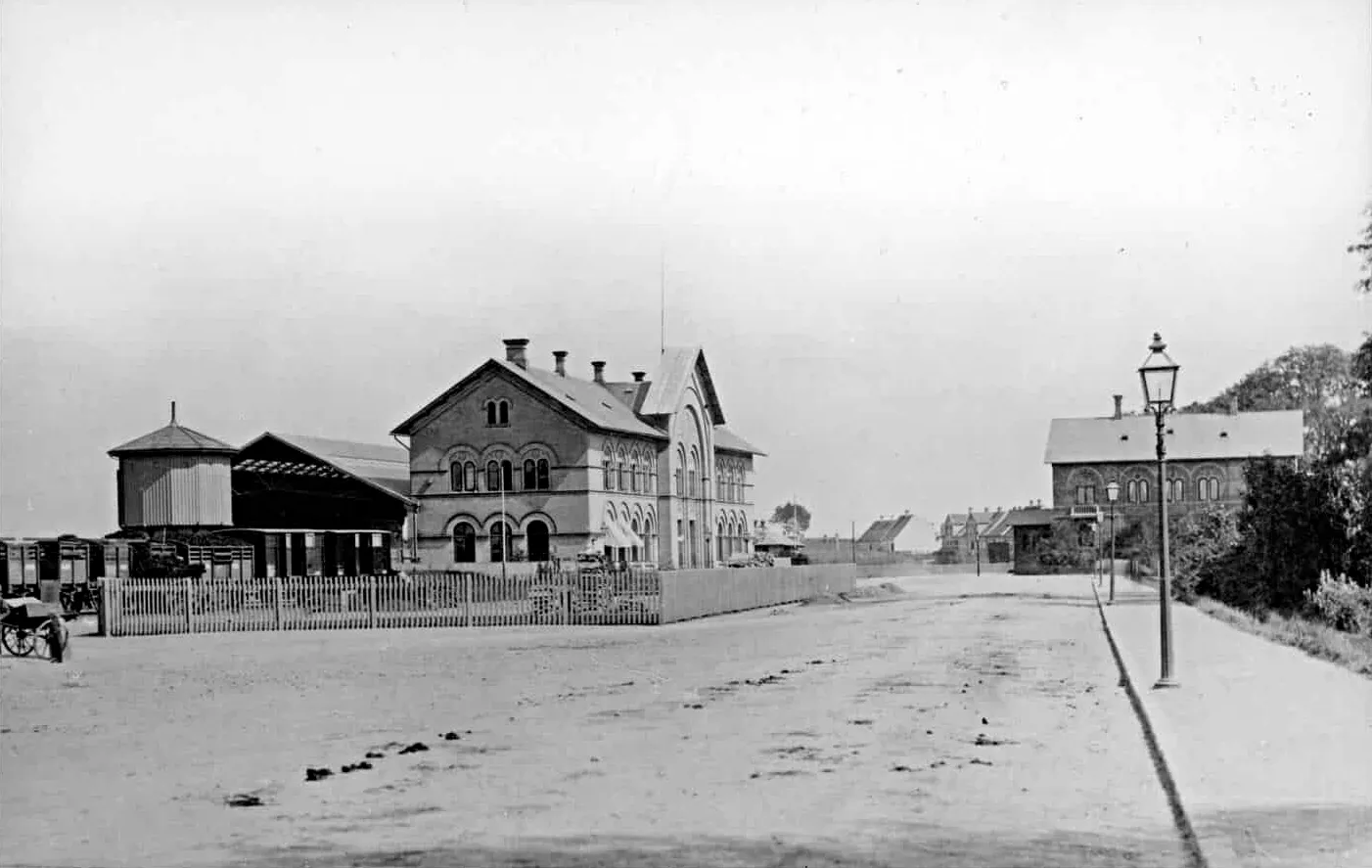 Billede af Odense Banegård - de lave bygninger i baggrunden er huse i Dannebrogsgade. Bygningen til højre er det nye banegårdsposthus, som blev revet ned i 1895. Billede af Odense Banegård - de lave bygninger i baggrunden er huse i Dannebrogsgade. Bygningen til højre er det nye banegårdsposthus, som blev revet ned i 1895.